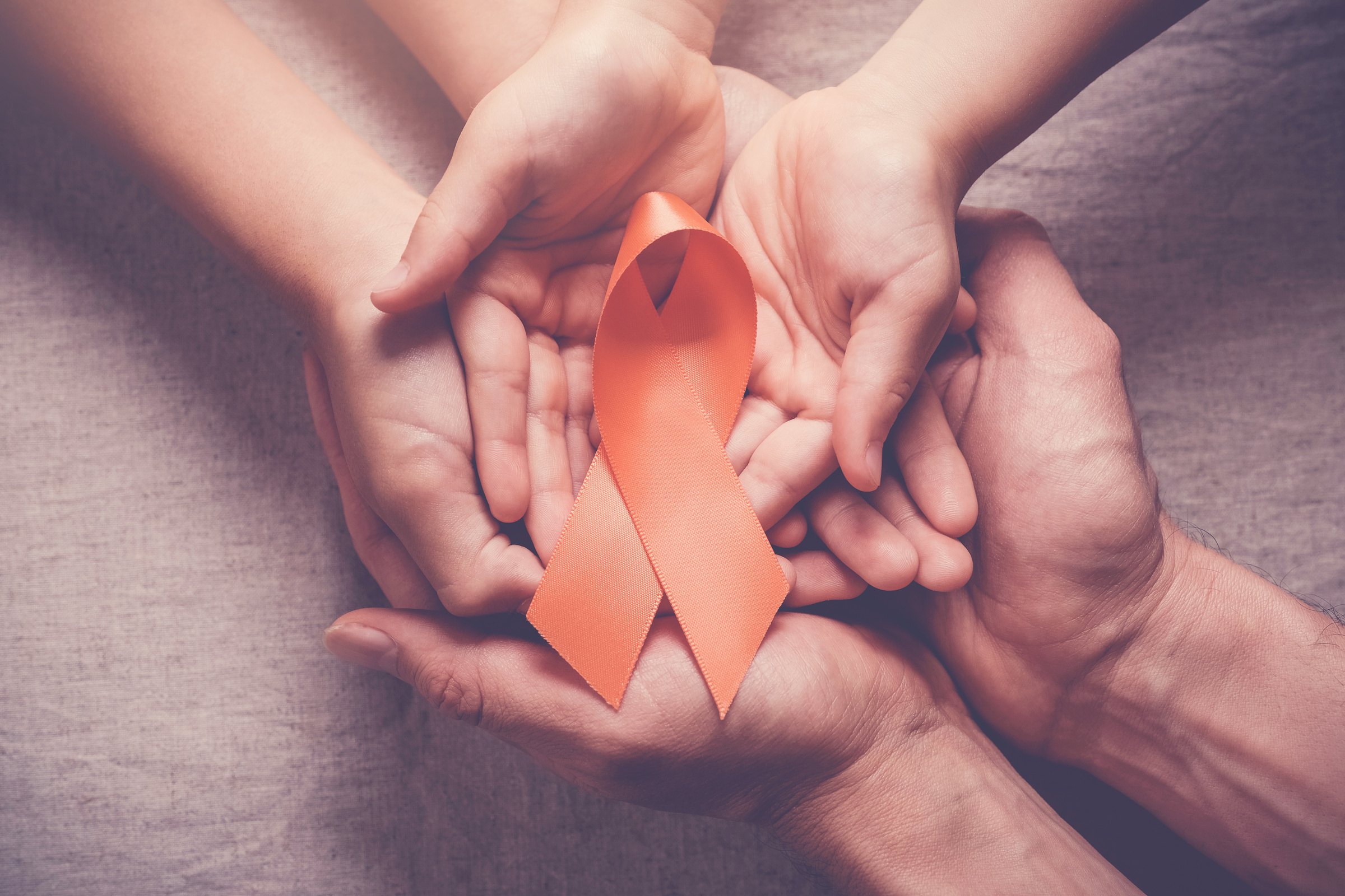 Adult and child hands holding orange Ribbons,  Leukemia cancer and Multiple sclerosis, COPD and ADHD awareness, world kidney day